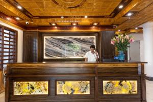 a man talking on a cell phone behind a reception desk at Royal Hotel Sài Đồng - Long Biên in Hanoi