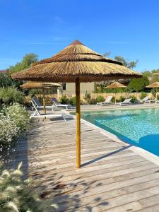 a wooden path with a straw umbrella and a swimming pool at Duplex Marina Rossa in Lecci