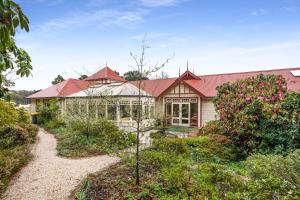 una casa con techo rojo y jardín en Bethany Manor B&B call them for Guaranteed Cheapest Price, en Leura
