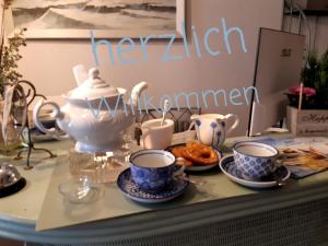 una mesa con tazas y platillos y un cartel que lee inflamación de la cocina en Aparthotel Domizil en Borkum