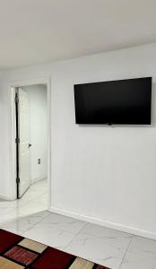 telewizor z płaskim ekranem na białej ścianie w pokoju w obiekcie Miad’s Guest House w mieście Jamaica