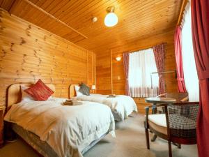 a bedroom with two beds and a wooden wall at Madarao Vacance Village in Iiyama