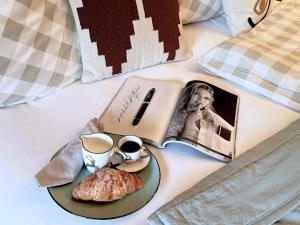 a breakfast plate with a book and coffee and a pastry on a bed at KitzMoments by Belle Stay in Reith bei Kitzbühel