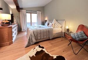 a bedroom with a bed and a chair and a window at KitzMoments by Belle Stay in Reith bei Kitzbühel