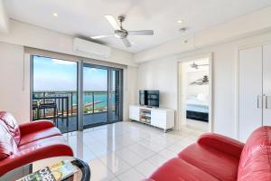 a living room with a red couch and a view of the ocean at Darwin City - The Oaks with Harbour Views in Darwin
