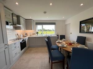 a kitchen with a wooden table and blue chairs in a kitchen at Dell View - Charming & Cosy in Bentley