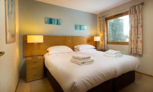 a bedroom with a large bed with towels on it at Keswick Bridge Lodge Resort in Keswick