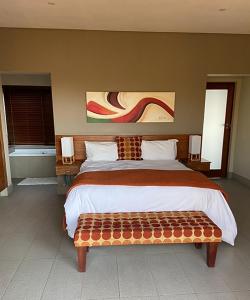 um quarto com uma cama grande e um banco em Elements Golf Reserve House 303 em Moheme