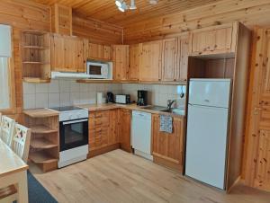 cocina con armarios de madera y nevera blanca en Twin Peaks Urupää A Saariselkä en Saariselka