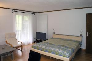 a bedroom with a bed and a chair and a television at 6303 Komplett renoviertes und stilvolles Studio zum Wohlfuehlen in Vulpera