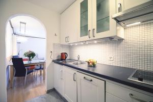 a kitchen with white cabinets and a sink and a table at 6303 Komplett renoviertes und stilvolles Studio zum Wohlfuehlen in Vulpera