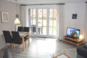 een woonkamer met een eettafel en een televisie bij Ostseeallee 9 Ferienwohnung Nr 01 in Niendorf