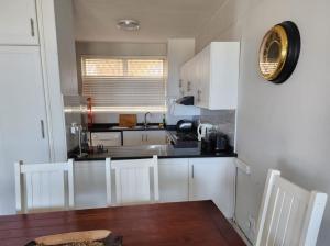 a kitchen with white cabinets and a black counter top at Casa Uvongo 110 in Uvongo Beach