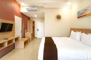 a bedroom with a large bed and a tv at Agro Hotel Bintan in Telukbakau