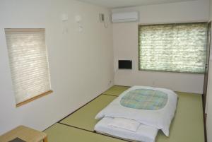 Cette chambre comprend un lit et deux fenêtres. dans l'établissement Pension Megumiyuki, à Biei