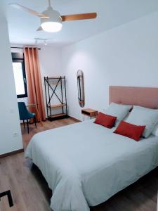 - une chambre avec un grand lit blanc et des oreillers rouges dans l'établissement Aromas del Jiloca, la Trufa Negra, à Calamocha