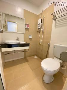 a bathroom with a toilet and a sink at Havona Hotel - Kulai in Kulai