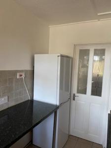 een keuken met een witte koelkast naast een deur bij Laret Guest House in Londen