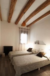 2 camas en una habitación con paredes blancas y ventana en Casa Fonset, en Àger