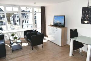 un soggiorno con TV, tavolo e sedie di Strandhotel Appartement Nr 33 a Niendorf