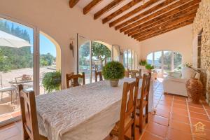 a dining room with a table and chairs and windows at Villa Katerina in Benissa