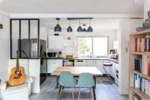 a kitchen with a table and chairs and a guitar at Appartement avec balcon au Canal Saint-Martin in Paris