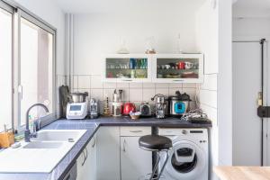 a white kitchen with a washing machine and a sink at Appartement avec balcon au Canal Saint-Martin in Paris