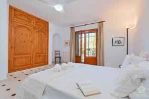 um quarto com uma cama branca e um armário de madeira em Villa Katerina em Benissa