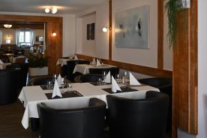 a restaurant with white tables and black chairs at Hôtel de la Gare in Saignelégier