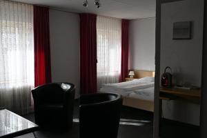 a hotel room with a bed and two chairs at Hôtel de la Gare in Saignelégier
