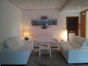 ein Wohnzimmer mit 2 weißen Sofas und einem Tisch in der Unterkunft Hotel Moreri in Grado