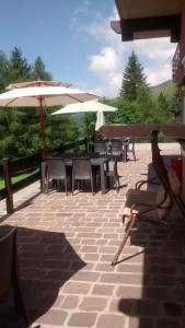 a patio with tables and chairs and umbrellas at Albergo Ristorante Pineta in Collio