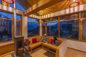 two people sitting on a bench in a room with windows at Zostel Old Manali in Manāli