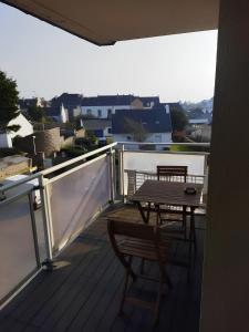 Studio au coeur de Quiberon في كويبيرون: سطح خشبي مع طاولة وكراسي على شرفة +صورتان