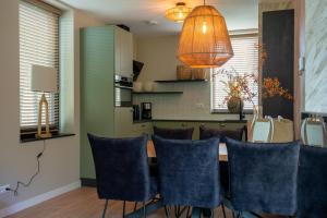 a dining room with a table and blue chairs at Parc La Dune Dutch Lodge in Warmenhuizen