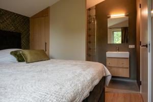 een slaapkamer met een groot bed en een wastafel bij Parc La Dune Dutch Lodge in Warmenhuizen