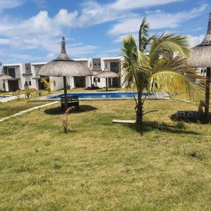 een resort met een palmboom en een zwembad bij North Mauritius New-built 2-bedroom Villa with shared pool in Grand Gaube