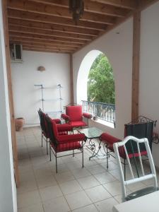 eine Veranda mit roten Stühlen, einem Tisch und einem Fenster in der Unterkunft Kamel 114 in Houmt Souk