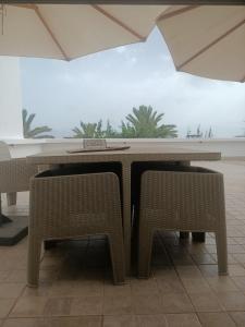 a table and two wicker chairs in a room at Kamel 114 in Houmt Souk