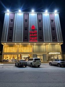 un edificio con coches aparcados delante de él por la noche en لاقونا للشقق المخدومة, en Al-Hasa