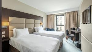 a hotel room with two beds and a desk at Mercure Edinburgh Haymarket in Edinburgh +37 photos
