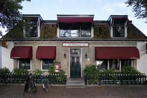 a brick house with red awnings on it at De Welvaart - Logement in Hollum