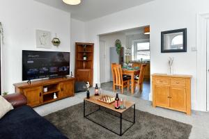 a living room with a couch and a tv and a table at Spacious 2 bedroom apartment in the heart mumbles in The Mumbles