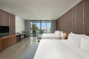 a hotel room with two beds and a flat screen tv at Avora Hotel in Danang