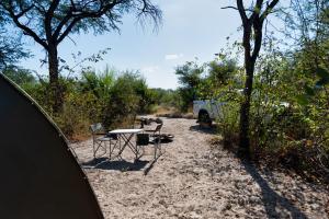 a table and chairs sitting in the sand next to a van at Semowi Lodge and Campsites in Mirapene