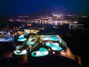 a group of swimming pools at night at Agalia Luxury Suites in Tzamaria