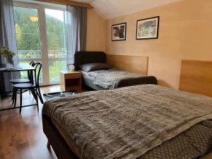 a bedroom with two beds and a table and a window at Apartmány Gryf Harrachov in Harrachov