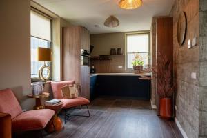 een woonkamer met een bank en een stoel en een keuken bij Parc La Dune Marrakesh Lodge in Warmenhuizen