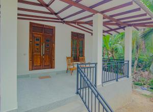 un porche de una casa con puerta de madera en King Coco Villa Hikkaduwa en Galle