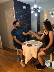 un hombre y una mujer sentados en una mesa con copas de vino en Central and Affordable house in Williamsburg Close to Subway en Brooklyn